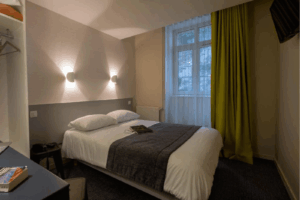 Chambre Standard de l’Hôtel du Port à Morlaix Chambre standard de l’Hôtel du Port à Morlaix avec lit double, éclairage chaleureux et vue extérieure.